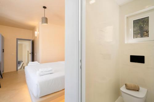 a white room with a bed and a toilet at Eolithos Exclusive Suites in Éxo Goniá