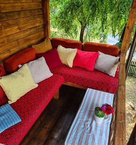 a red couch with colorful pillows on a porch at Turističko-seosko gazdinstvo Hajdana in Surdulica