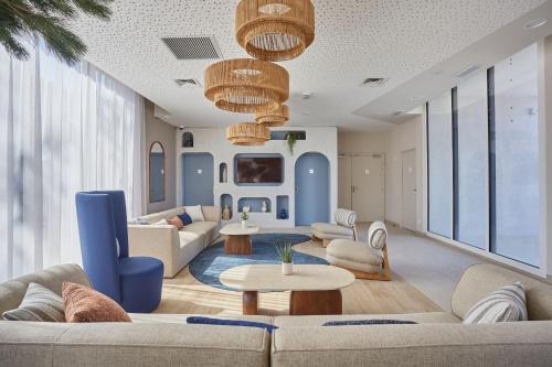a living room with couches and tables and windows at Résidence Odalys Riviera in Hyères