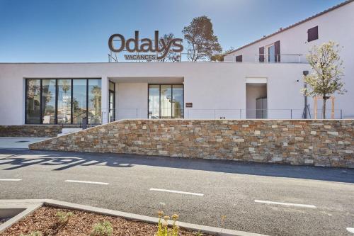 a white building with a stone wall and a sign on it at Résidence Odalys Riviera in Hyères