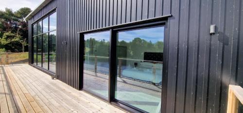 a house with large glass windows on a wooden deck at Otters Cove, Middleton Hall Estate in Belford
