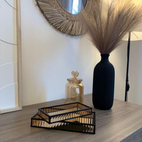 a black vase sitting on a table with a mirror at Bilocale nuovo - Basiglio Humanitas in Basiglio
