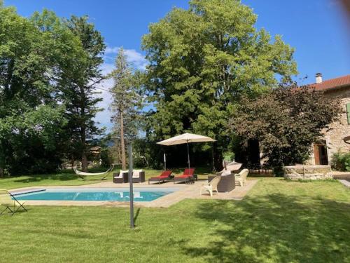 a yard with a swimming pool with chairs and an umbrella at La Bastide de combe laval in Saint-Laurent-en-Royans
