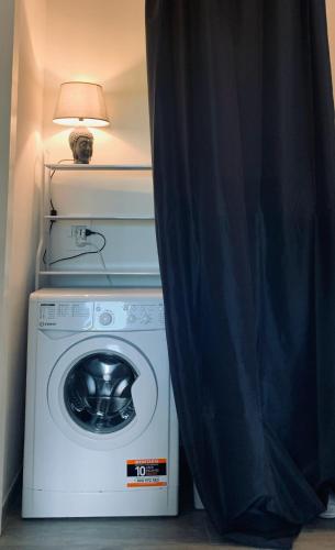 a room with a washing machine with a lamp and a curtain at Bilocale nuovo - Basiglio Humanitas in Basiglio