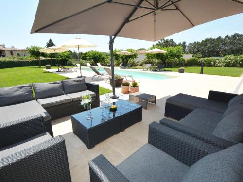 une terrasse avec des canapés, un parasol et une piscine dans l'établissement Apartment Le Mas des Trois Anges-1 by Interhome, à Saint-Denis