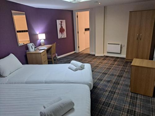 a hotel room with two beds with towels on them at Britannia Edinburgh Hotel in Edinburgh