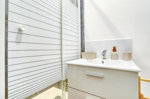 une salle de bain blanche avec un lavabo et une douche dans l'établissement Le studio Duret II, à Paris