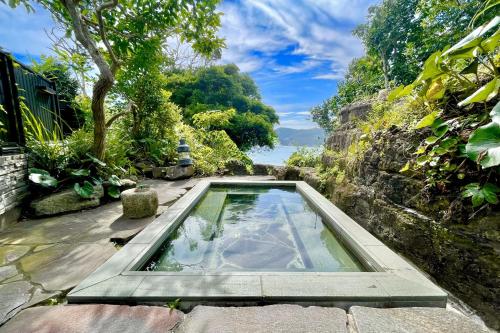 a swimming pool in the middle of a garden at 鵜原館 -Ubarakan- in Katsuura