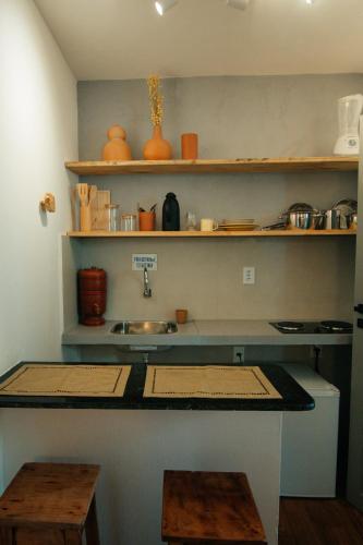 a kitchen counter with a sink and shelves at Pousada Girassol Morro de São Paulo in Morro de São Paulo