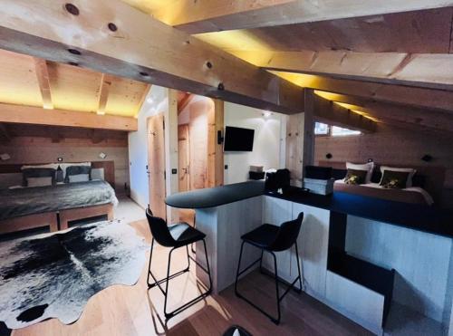 a room with a bed and a bar with chairs at Chalet-Hôtel Inarpa in La Clusaz