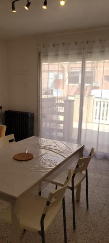 une table blanche et des chaises dans une pièce avec une fenêtre dans l'établissement Superb T2 near the beach of Port-la-Nouvelle, à Port-la-Nouvelle