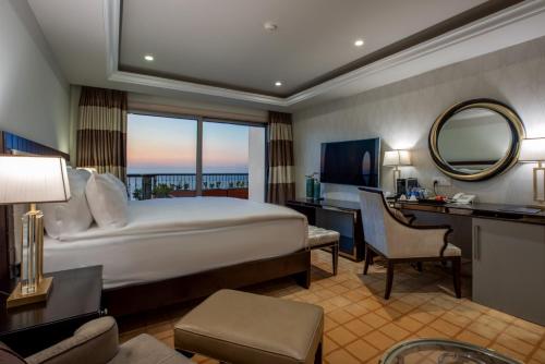 a hotel room with a bed and a desk and a mirror at Liman Hotel & Casino by Merit in Kérynia