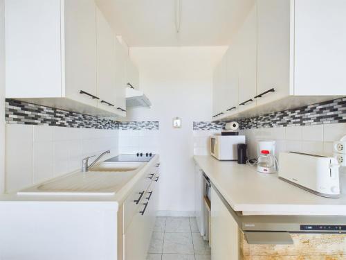 a kitchen with white cabinets and a sink at Appart pour 4 - Loggia vue mer - 250m de la plage in Plage-des-Demoiselles