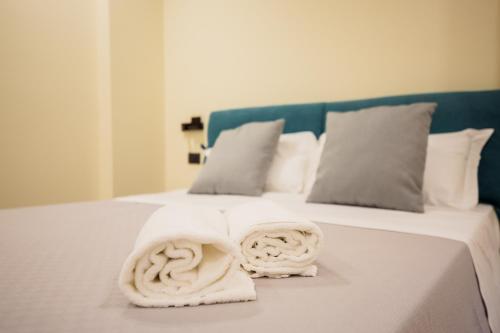 a white bed with two rolled towels on it at MAZZINI PALACE in Misterbianco