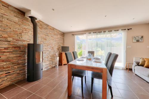 une salle à manger avec une table et un mur de briques dans l'établissement 1km de la plage, maison neuve avec jardin pour 4, à Sarzeau