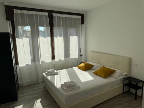 a bedroom with a bed with yellow pillows and a window at FEEL - Casa Centrale Bergamo in Bergamo