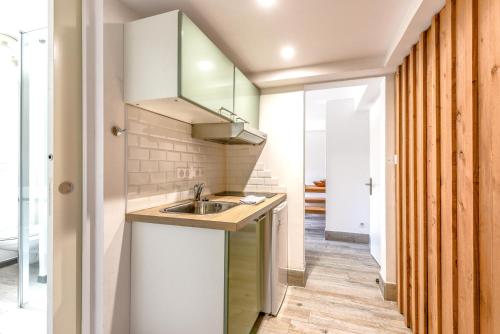 - une petite cuisine avec un évier et un miroir dans l'établissement Villa Violette - Piscine privée, à Gujan-Mestras