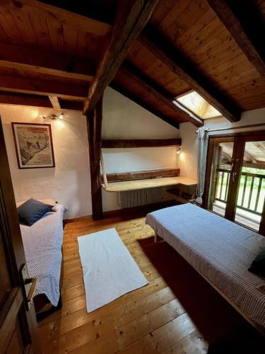 - une chambre mansardée avec 2 lits et une fenêtre dans l'établissement La ferme de la Tour - Vallée de Chamonix, à Servoz