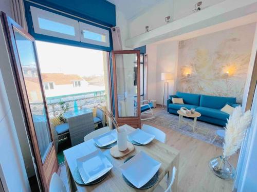 un salon avec une table et un canapé bleu dans l'établissement Saint Maurice -T2 accès privé mer YourHostHelper, à Palavas-les-Flots