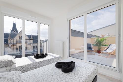 two beds in a room with a large window at La Terrasse de l'Eglise, Paris Center & Eurostar 15 mn, Brand new duplex with terrasse, balcony, 2 bathrooms, parking, in Saint-Denis