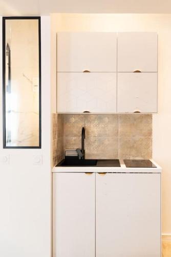 une cuisine avec des armoires blanches et un évier dans l'établissement Elégant studio DIVINE SUN quartier Canal St Martin, à Paris