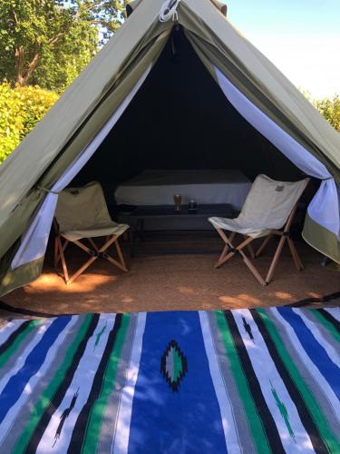 une tente avec deux chaises et un lit dans l'établissement Le Clos des Reines, à Conteville