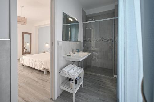 a bathroom with a sink and a shower and a bed at Dimora del Corso - Rooms in Mattinata