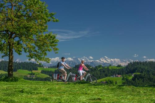 two people riding bikes on a grassy hill at Hotel Bären in Sumiswald