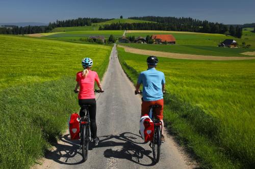 a man and woman riding bikes down a road at Hotel Bären in Sumiswald