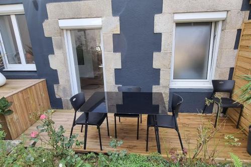 a black table and chairs in front of a building at Le P'tit Patio, Terrasse privative. in Lanester