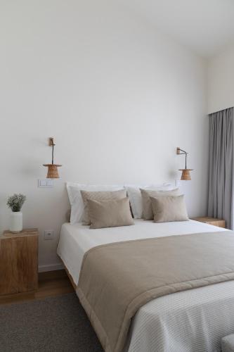 a bedroom with a large bed with white sheets and pillows at Casa da Milheira - Agroturismo in Oliveira de Azemeis