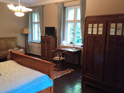 a bedroom with a bed and a desk and windows at Villa Pepita in Miedzygorze