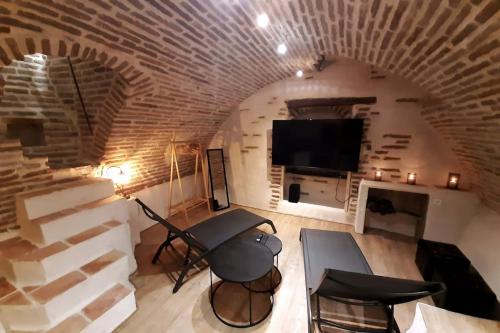 a living room with a brick wall and a tv at Studio et spa privatif Le Puits de la Grâce in Albi