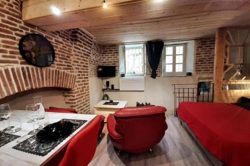 a living room with red furniture and a brick wall at Studio et spa privatif Le Puits de la Grâce in Albi