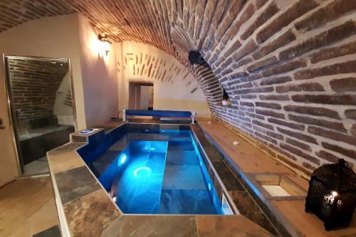 a swimming pool in the middle of a brick wall at Studio et spa privatif Le Puits de la Grâce in Albi
