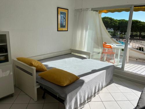 - une chambre avec un lit doté d'oreillers jaunes et un balcon dans l'établissement Studio Anny climatisé vue mer avec piscine, au Grau-du-Roi