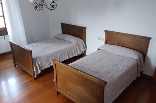 two beds in a room with wooden floors at Casa do Souto in Ferrol