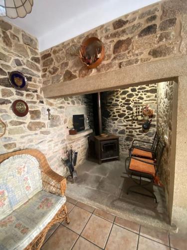 a room with a stone wall with a chair and a stove at Casa do Souto in Ferrol