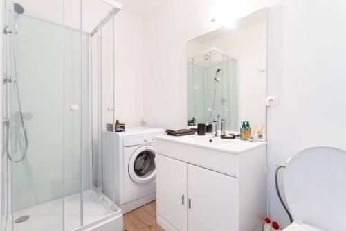 une salle de bain blanche avec une machine à laver et un lavabo dans l'établissement En hauteur - Appartement élégant proche du métro, à Mons-en-Baroeul