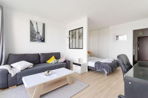 un salon avec un canapé et un lit dans l'établissement En hauteur - Appartement élégant proche du métro, à Mons-en-Baroeul