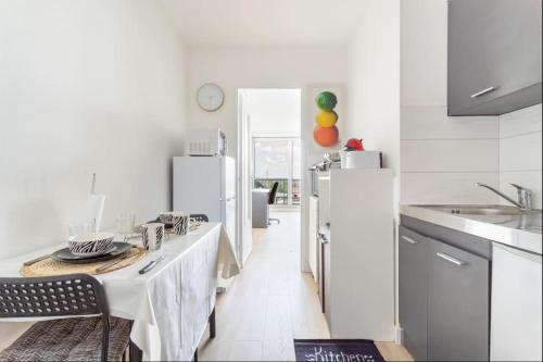 une cuisine blanche avec une table et un réfrigérateur dans l'établissement En hauteur - Appartement élégant proche du métro, à Mons-en-Baroeul