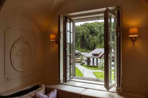 a living room with a large window with a view of a yard at Rosewood Schloss Fuschl in Hof bei Salzburg