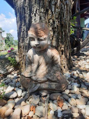 a statue of a child sitting on rocks next to a tree at Bačalandia- relax na samote in Veľká Dolina