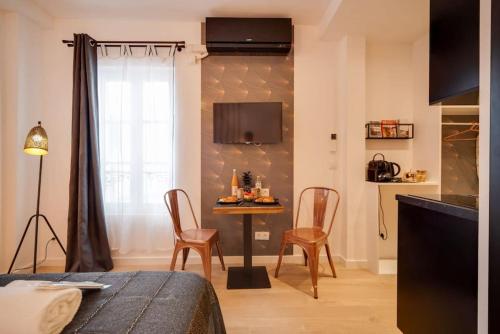 un salon avec une table, des chaises et une télévision dans l'établissement Stunning studio near Canal St Martin - DIVINE MOON, à Paris