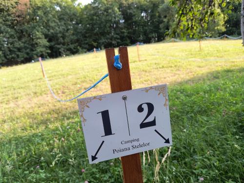 a sign on a wooden post in a field at Poiana Stelelor in Văleni