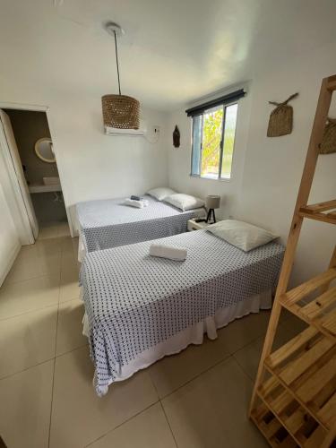 two beds in a room with a window at Maré suites in Fernando de Noronha