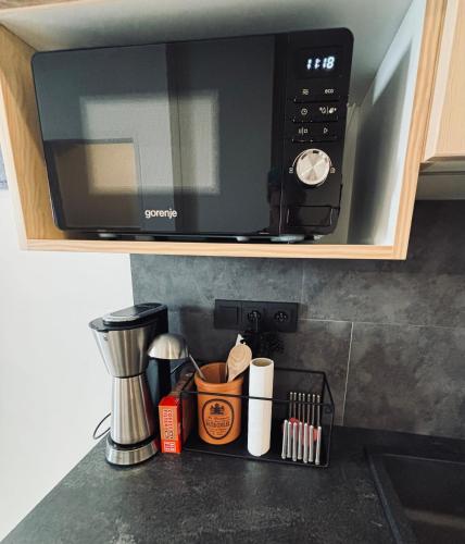 a microwave oven above a kitchen counter with utensils at Apartmány Panorama Harrachov in Harrachov