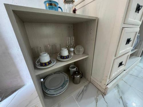 a small cabinet with plates and dishes on it at Lindo Chalé Rústico 8 min do centrinho turístico in Campos do Jordão