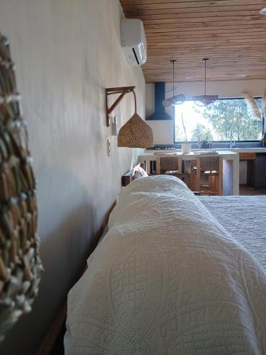 a white bed in a room with a kitchen at Alto Curanipe in Pelluhue