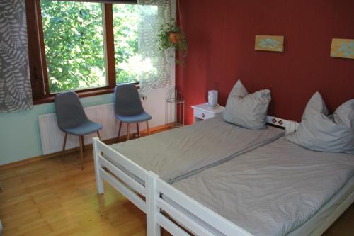 a bedroom with a white bed and two chairs at Ferienhaus am Belmermoor 167 in Brunsbüttel